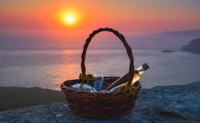 Picnic basket with wine and glasses at sunset by the sea